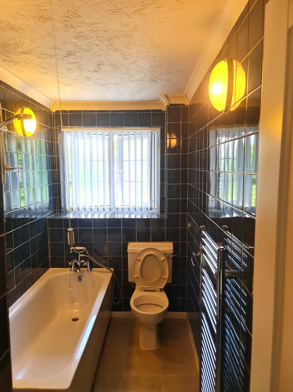 Bath, toilet and towel rails in navy-tiled finished bathroom